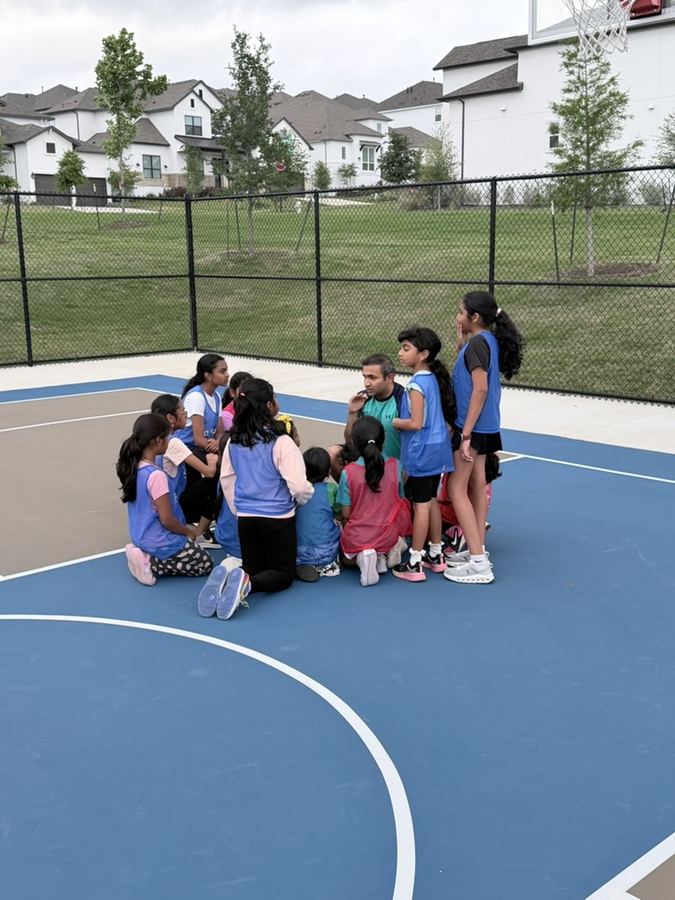 Kids in a huddle with a coach on the court